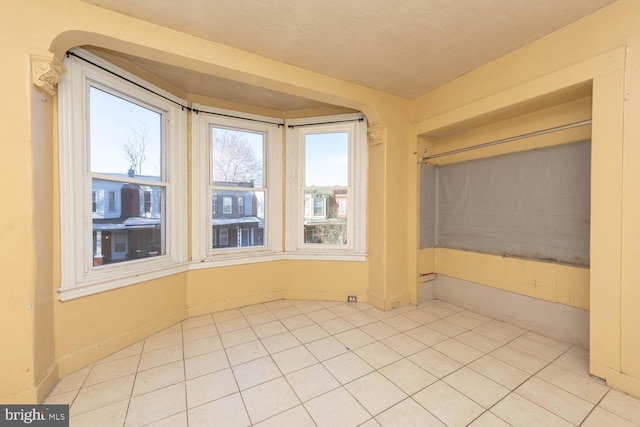 tiled empty room featuring a textured ceiling