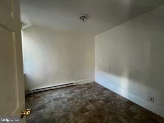 spare room with baseboard heating, lofted ceiling, and dark colored carpet