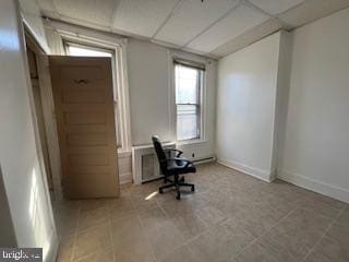 interior space with a paneled ceiling and light tile patterned flooring