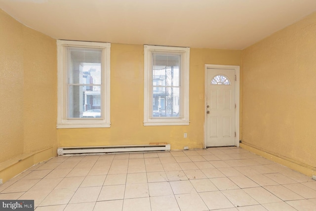 foyer entrance with baseboard heating, light tile patterned floors, and a healthy amount of sunlight