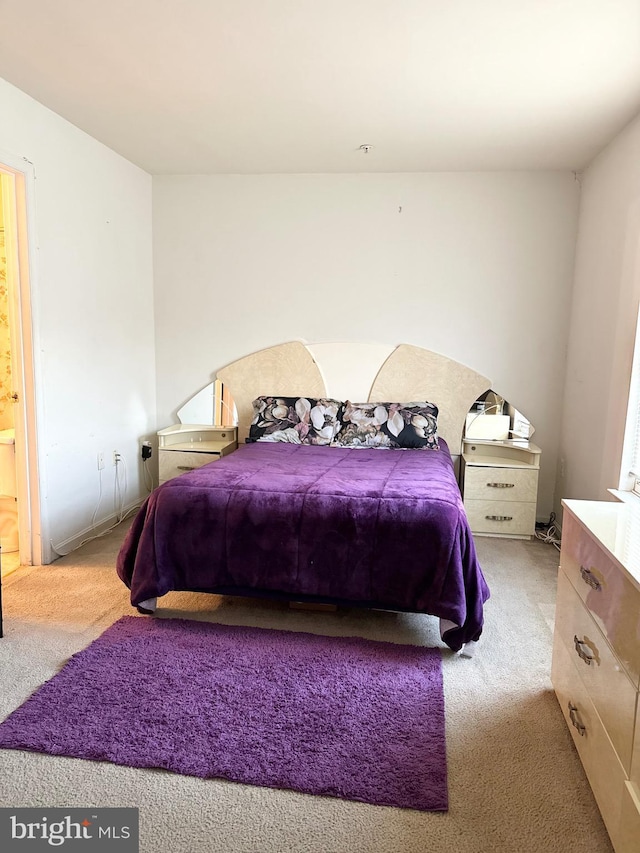 bedroom with ensuite bathroom and light colored carpet