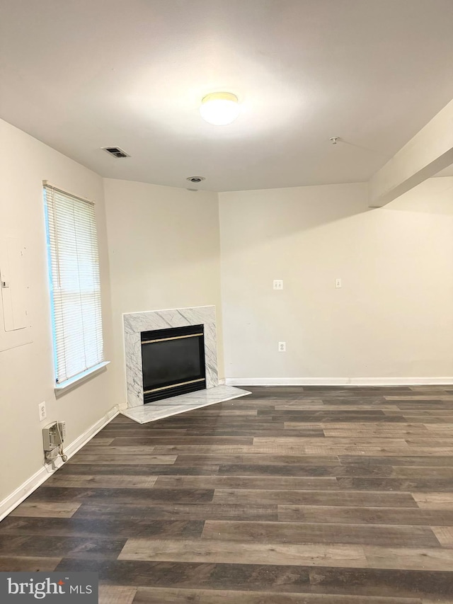 unfurnished living room with a premium fireplace and dark wood-type flooring