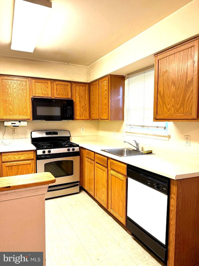 kitchen with white dishwasher, sink, and stainless steel gas range