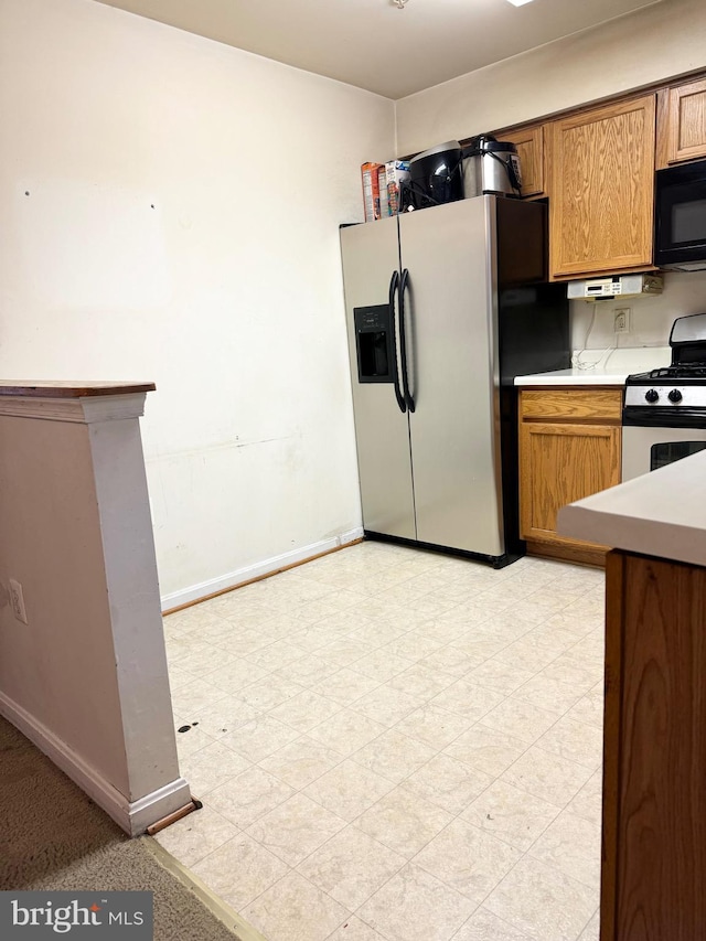 kitchen featuring stainless steel fridge with ice dispenser and white gas range oven