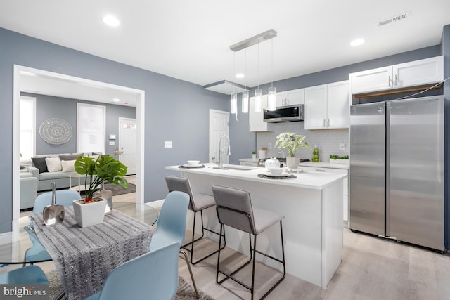 kitchen with sink, hanging light fixtures, stainless steel appliances, tasteful backsplash, and white cabinets