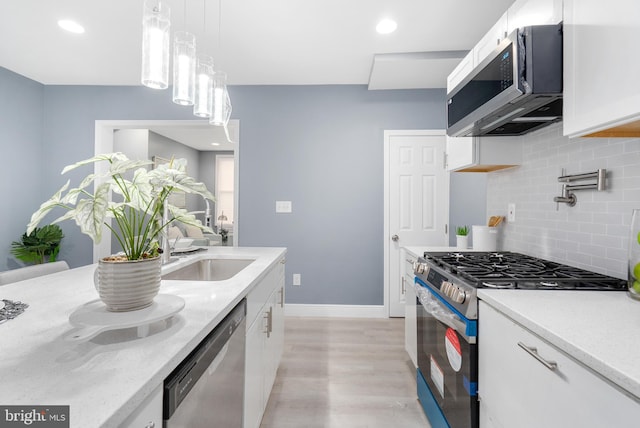 kitchen featuring pendant lighting, light hardwood / wood-style floors, white cabinetry, and stainless steel appliances