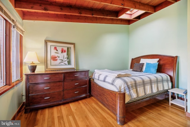 bedroom featuring a skylight, beamed ceiling, wood ceiling, and light wood-type flooring