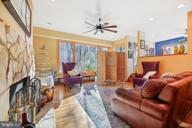 living room with ceiling fan, a fireplace, and light hardwood / wood-style floors