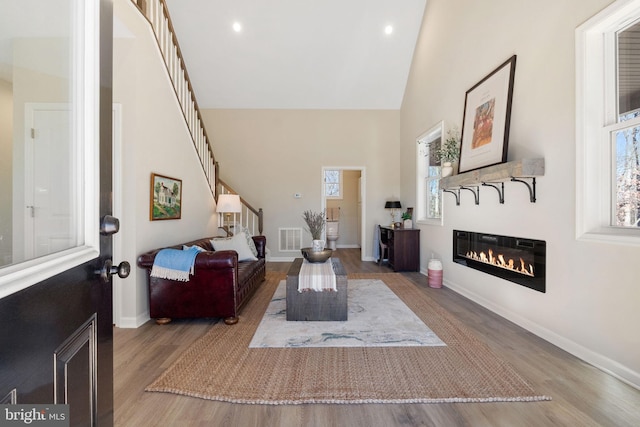 living room with light wood-type flooring and high vaulted ceiling