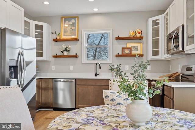 kitchen with stainless steel appliances, white cabinets, sink, and light hardwood / wood-style floors