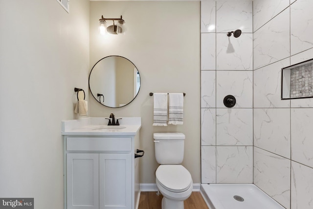 bathroom featuring vanity, tiled shower, toilet, and hardwood / wood-style flooring