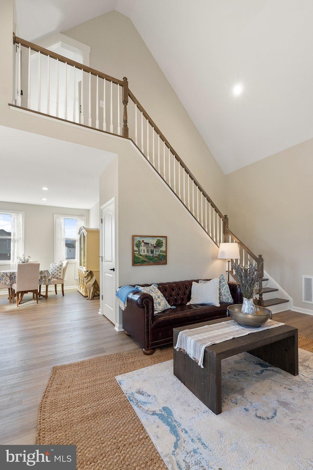 living room with high vaulted ceiling and wood-type flooring