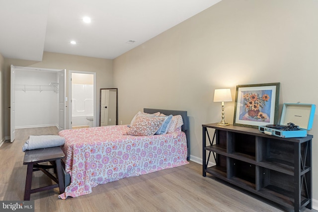 bedroom with ensuite bath, a closet, hardwood / wood-style floors, and a spacious closet