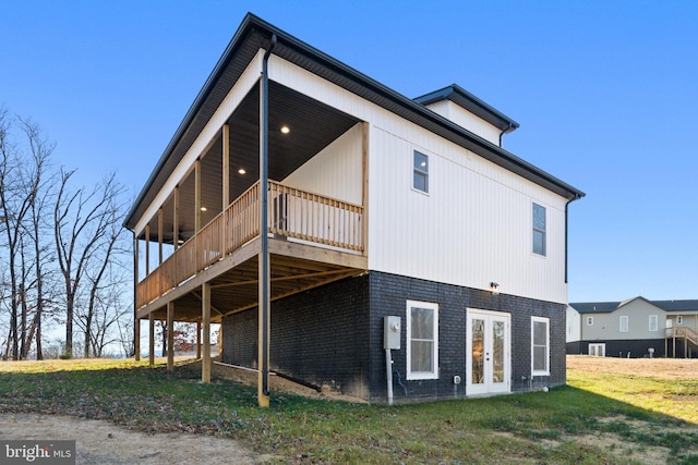 back of house with a deck, french doors, and a yard