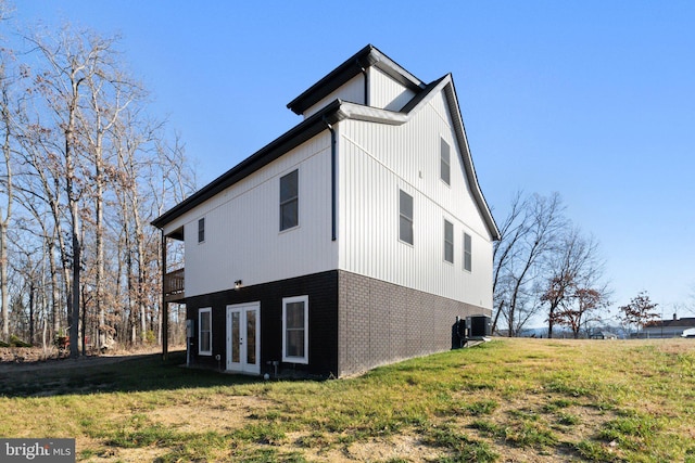 view of side of property featuring central air condition unit, french doors, and a yard