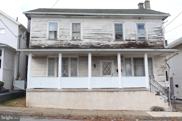 view of front of home featuring covered porch and a chimney