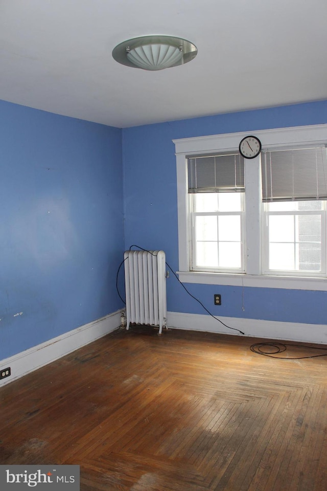 unfurnished room featuring hardwood / wood-style flooring and radiator heating unit