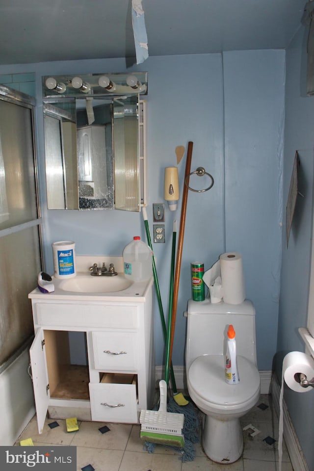 bathroom with tile patterned flooring, vanity, toilet, and a shower with shower door