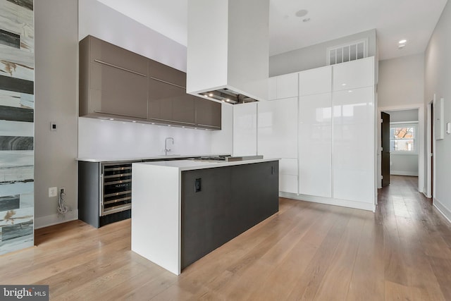 kitchen featuring white cabinetry, sink, a center island, light wood-type flooring, and custom exhaust hood