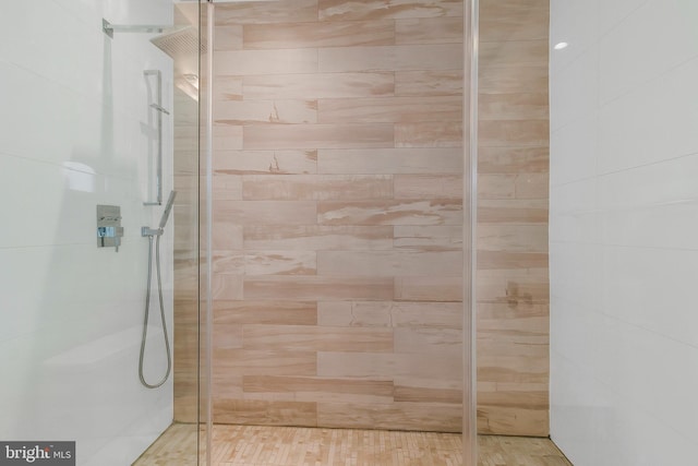 bathroom with a tile shower and wood-type flooring