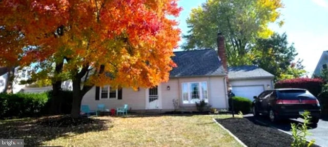 view of property hidden behind natural elements with a front yard and a garage