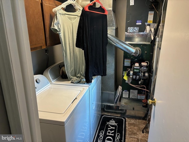 laundry room featuring washer and clothes dryer, cabinets, and dark tile patterned flooring