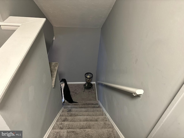 stairs featuring carpet and a textured ceiling