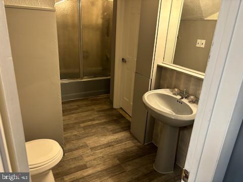 bathroom featuring hardwood / wood-style flooring, toilet, an enclosed shower, and sink