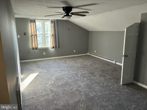 bonus room featuring ceiling fan, dark carpet, lofted ceiling, and a baseboard heating unit