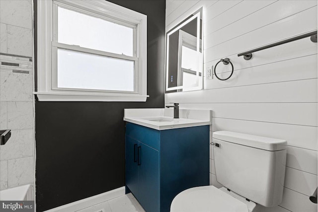 bathroom featuring a washtub, vanity, and toilet