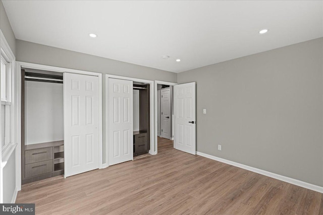 unfurnished bedroom with multiple closets and light hardwood / wood-style flooring