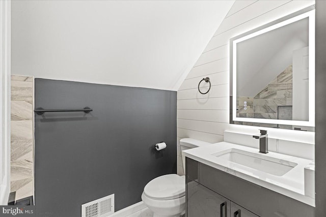 bathroom with vanity, toilet, and lofted ceiling