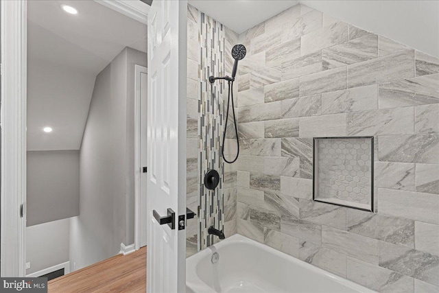 bathroom with hardwood / wood-style flooring and tiled shower / bath