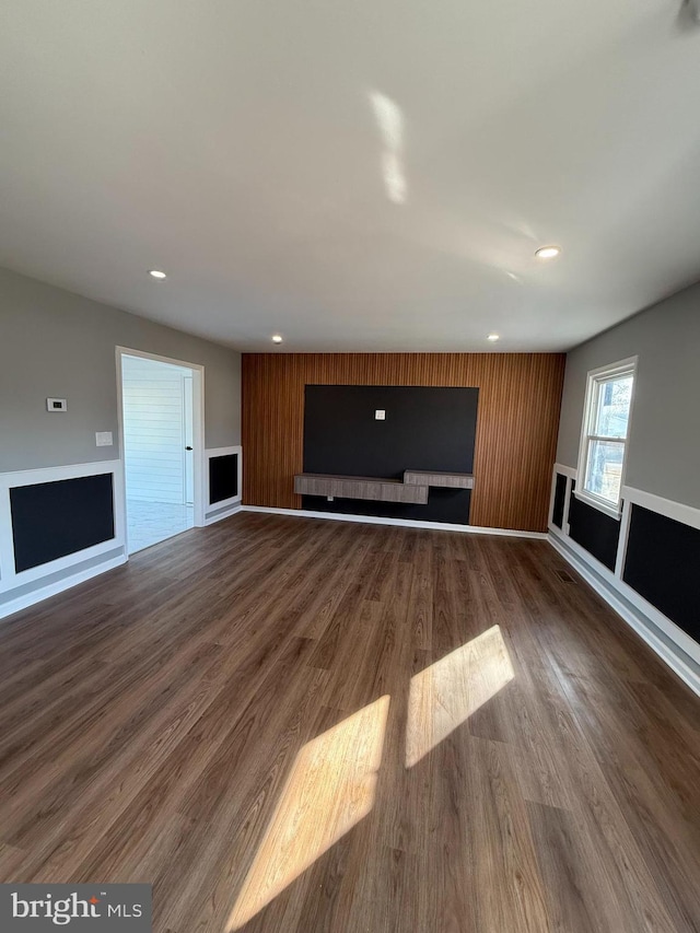 unfurnished living room with wood walls and dark hardwood / wood-style flooring