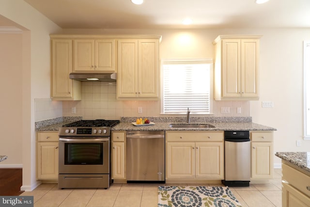 kitchen with light stone counters, sink, light tile patterned floors, and stainless steel appliances