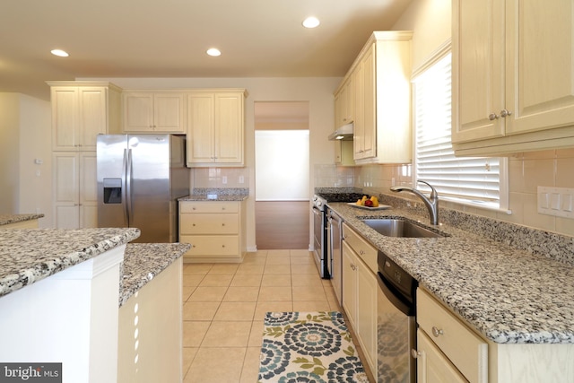 kitchen featuring light stone countertops, tasteful backsplash, stainless steel appliances, sink, and light tile patterned floors