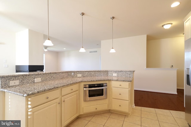 kitchen with hanging light fixtures, ceiling fan, light tile patterned floors, appliances with stainless steel finishes, and light stone counters