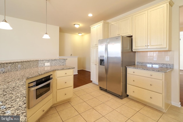 kitchen with light tile patterned floors, light stone countertops, hanging light fixtures, and appliances with stainless steel finishes