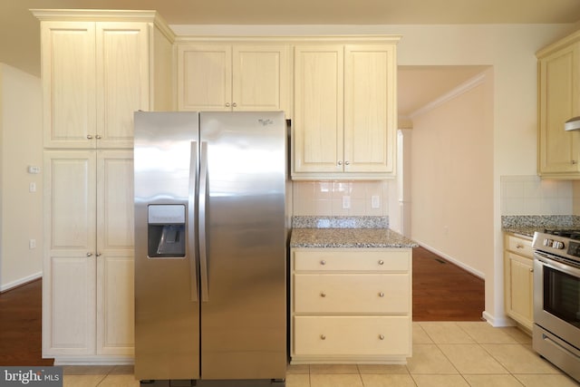 kitchen with light stone countertops, stainless steel appliances, tasteful backsplash, light tile patterned floors, and ornamental molding