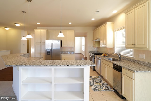 kitchen with light stone countertops, stainless steel appliances, sink, decorative light fixtures, and a kitchen island