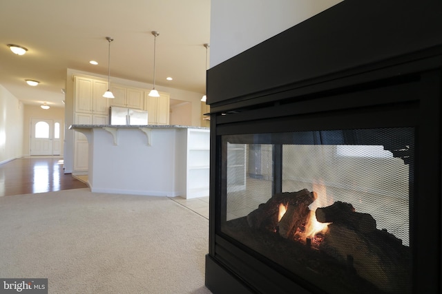 carpeted bedroom featuring a multi sided fireplace and stainless steel fridge