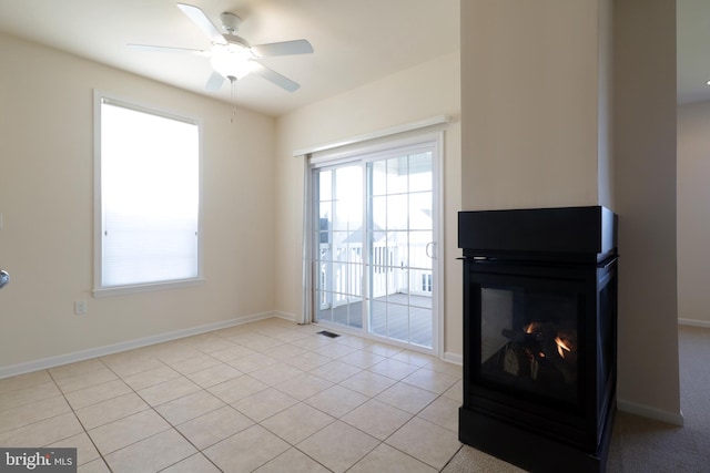 living room featuring a multi sided fireplace, light tile patterned floors, and ceiling fan