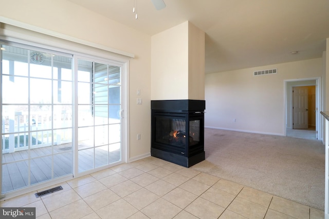 interior space featuring a multi sided fireplace, light carpet, and ceiling fan