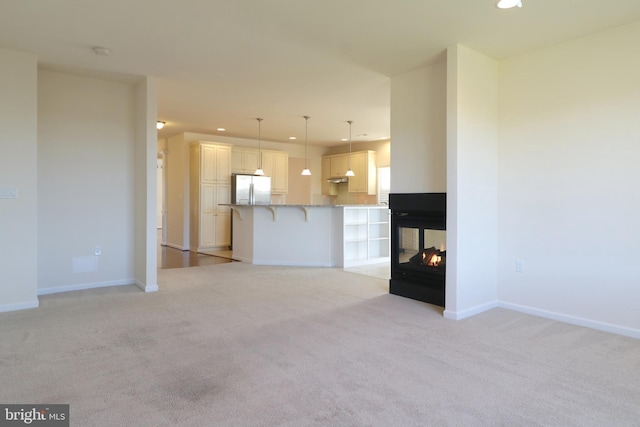 unfurnished living room with a multi sided fireplace and light colored carpet