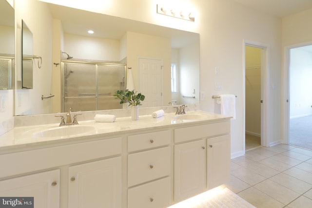 bathroom with tile patterned flooring, vanity, and a shower with door