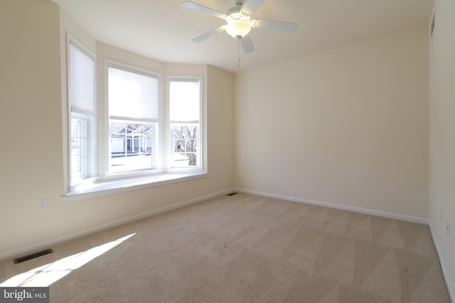 carpeted empty room with ceiling fan and plenty of natural light