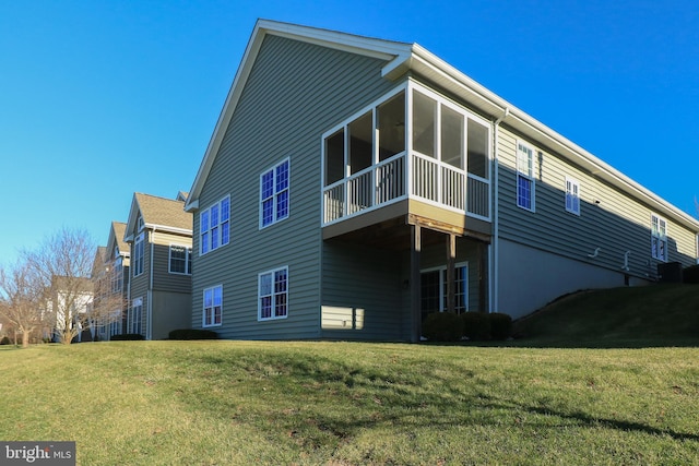 back of house featuring a sunroom and a lawn