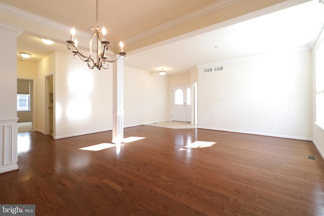 unfurnished room with dark hardwood / wood-style flooring, decorative columns, an inviting chandelier, and ornamental molding