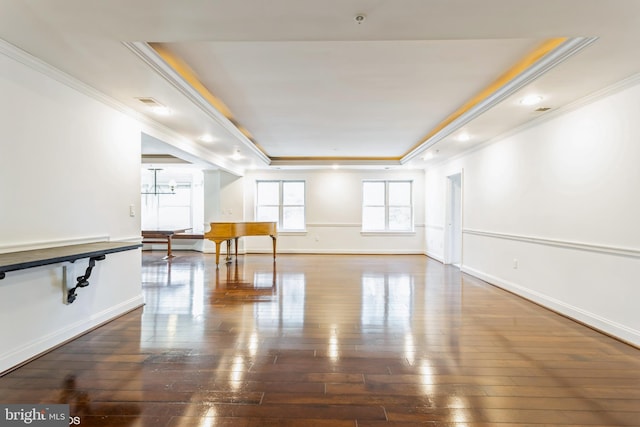 empty room featuring crown molding, dark wood-type flooring, and a tray ceiling