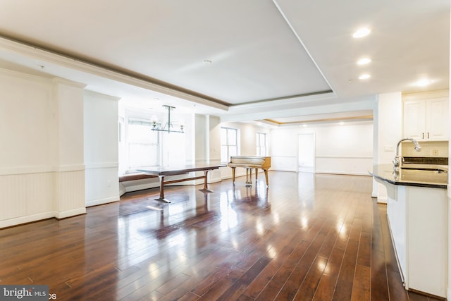 rec room featuring sink, an inviting chandelier, dark hardwood / wood-style flooring, a tray ceiling, and ornamental molding